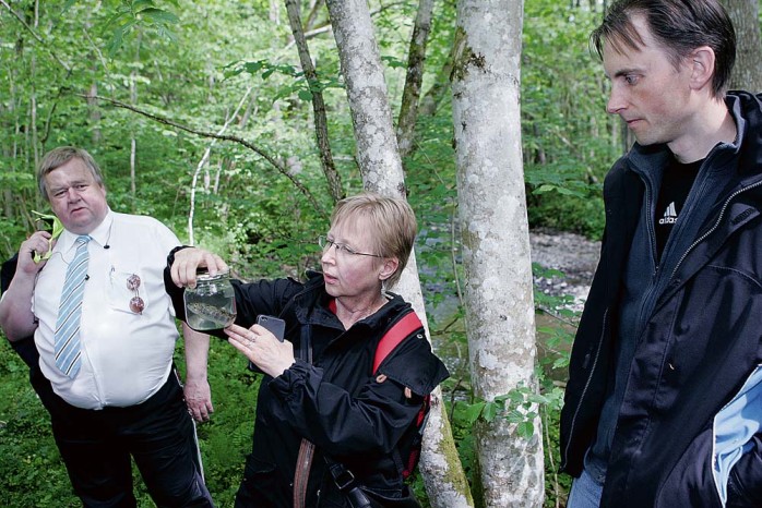 Ragnhild Kappelmark, enhetschef för allmänkulturen, studerar lax och öring på nära håll. Ragnhild flankeras av kommunfullmäktiges ordförande Klas Nordh och kommunekolog Göran Fransson.